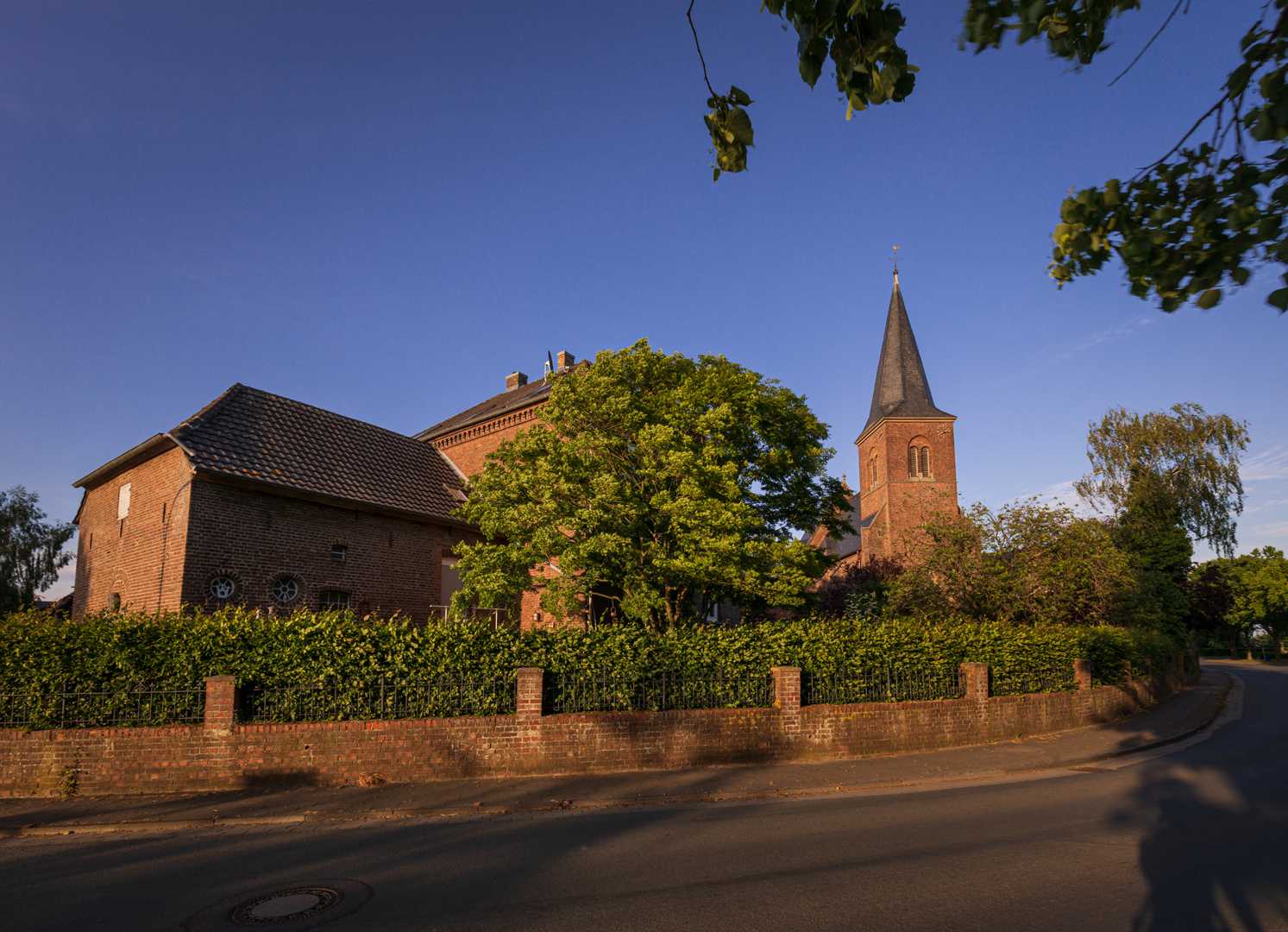 Foto der St. Peter Kirche in Huisberden mit blühenden Bäumen