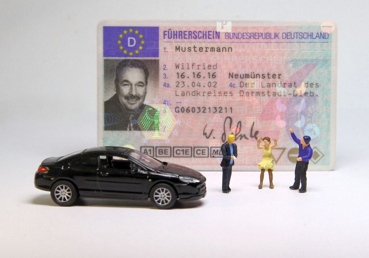 Foto mit einem Führerschein, einem Auto und drei Plastikfiguren