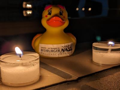 Foto einer Badeente bei Kerzenschein mit Hallenbad im Hintergrund